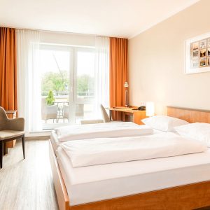 Doppelzimmer Komfort Spreeseite mit Doppelbett und Schreibtisch im Hintergrund. Blick zur Terrasse.